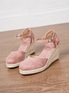 Dettaglio di sandali con zeppa rosa a punta chiusa con cinturino e suola in corda