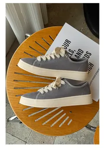 Dettaglio di sneaker retrò in tela grigia con lacci spessi su una sedia di legno