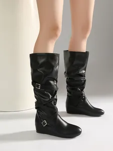 Detail of black mid-calf slouch boots with pleats and silver buckles on flat sole