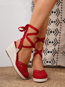 Detalle de sandalias de cuña tipo alpargata de ganchillo rojo con cintas.