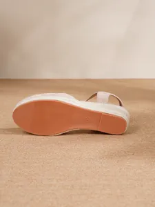 Primer plano de sandalias de cuña beige con suela antideslizante y plataforma de yute