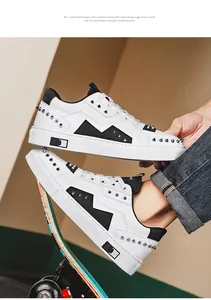 Trendy men's white sneakers with black lightning patch and silver rivets on a skateboard