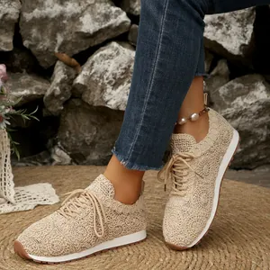 Detail view of beige crochet mesh lace-up sneakers worn outdoors on a woven mat
