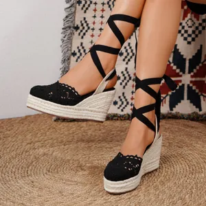 Elegantes sandalias de esparto con cuña de encaje negro y cintas para atar al tobillo.