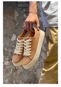 Primo piano di eleganti sneakers in tela marrone con suole spesse e lacci bianchi