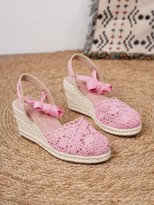 Detalle de encaje de ganchillo rosa en sandalias de cuña de alpargata para verano