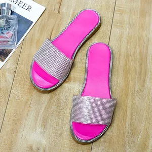 Detailweergave van modieuze platte strandsandalen met roze strassteentjes op houten achtergrond