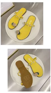 Detail view of yellow flat sandals with pineapple pearl ornament and textured anti-slip sole