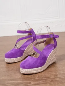 Gros plan de sandales compensées en daim violet avec plateforme en corde et boucle