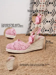 Detalle de sandalias con cuña de encaje rosa con tacón de paja de 8 cm y cintas