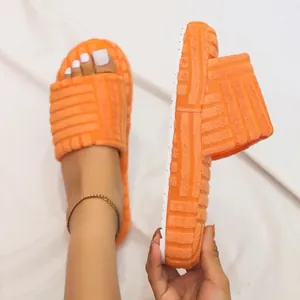 Detail of orange terry cloth slippers showing thick white sole and embossed pattern