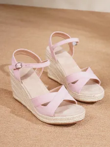 Detail view of pink suede wedge sandals with braided jute platform and ankle strap.