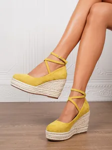 Sandalias de cuña amarillas de ante con plataforma de cuerda y correas al tobillo.