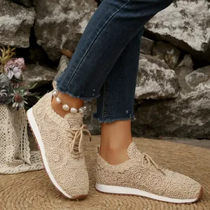 Detailed view of women's beige crochet lace sneakers worn with denim jeans on a mat.