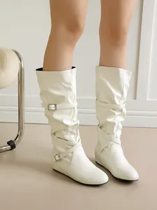Detailed view of white slouchy mid-calf boots featuring vintage buckle straps and flat heels.