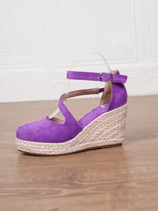 Gros plan sur des sandales compensées en daim violet avec talon en jute et bride