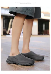 Detail showing grey suede backless clogs worn by a person on wooden floor