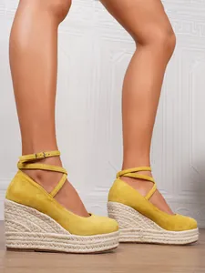 Detalle de alpargatas de cuña de ante amarillo con plataforma de cáñamo trenzado y correa