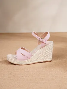 Side view of pink suede espadrille wedge sandal with ankle strap and woven sole