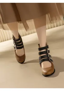 Detailed view of vintage brown Mary Jane boots with multi-buckle black straps