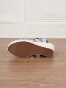 Detalle de cerca de la suela marrón antideslizante de estas sandalias de cuña azul pajizo