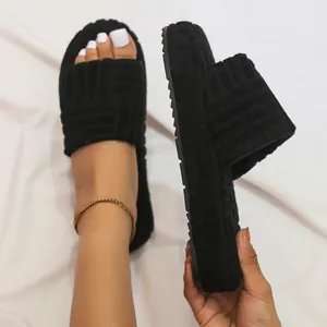 Close-up view of black embossed fuzzy slides with thick sole and plush texture.