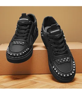 Close-up detail of black leather low-top sneakers with silver metal rivets and studs