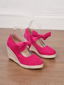 Elegantes sandalias de cuña fucsia con detalle de lazo y suela trenzada de paja
