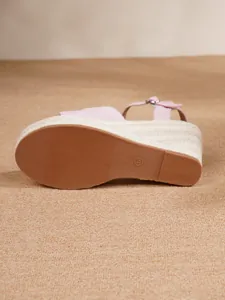Detailed view of the tan sole and straw-wrapped wedge of a pink espadrille sandal