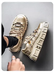 Dettaglio ravvicinato delle sneakers punk dorate con suola spessa su fondo grigio.