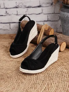 Detalle de las elegantes sandalias de cuña negras con suela rústica de yute trenzado