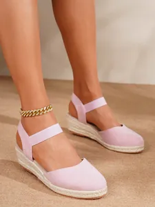 Primer plano de sandalias de cuña tipo alpargata rosas con punta cerrada y suela de yute
