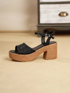 Detalle de sandalia negra de plataforma con tira trenzada y tacón ancho de corcho