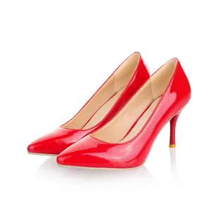 Détail de d'escarpins rouges vernis élégants à talons aiguilles sur fond blanc.