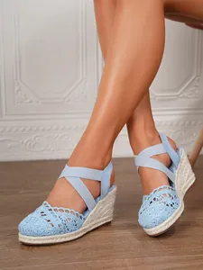 Detalle de sandalias con cuña de ganchillo azul claro con plataforma de esparto de cuerda