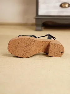Vista detallada de la suela de cuña con textura de corcho de estas sandalias chic.