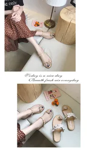Detailed view of women's beige flat sandals with elegant pearl straps and charms