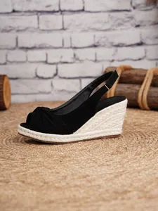 Detalle de sandalias de cuña de ante negro con plataforma de paja trenzada
