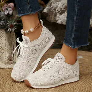 Detail of white crochet lace sneakers with intricate circular patterns and lace-up closure.