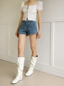 Detail view of white slouchy mid-calf boots with buckle straps and pleated leather.