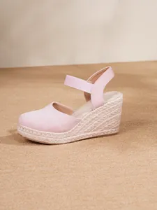 Detalle de sandalias de cuña de gamuza rosa con suela de cuerda de cáñamo trenzada.