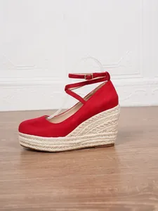 Detalle de una sandalia con cuña de ante rojo y plataforma de yute trenzado artesanal.