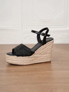 Detalle de sandalias de cuña trenzadas negras con plataforma de esparto y cuerda cáñamo