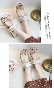 Close-up detail of stylish flat sandals with beaded pineapple and ruffle straps