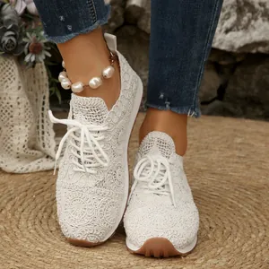 Close-up of white lace mesh sneakers with floral patterns and white laces on a model.