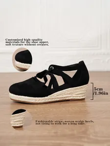 Detalle de perfil de sandalias de cuña en lona negra con tacón de paja trenzada de 5 cm