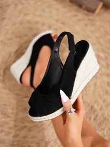 Detalle de sandalias de cuña negras con punta abierta anudada y tacón de cuerda esparto.