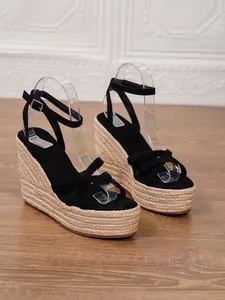 Close-up of black suede wedge sandals featuring woven espadrille platform soles