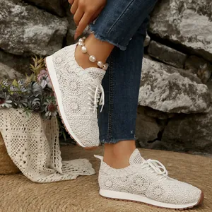 Detail view of white intricate lace sneakers on a model wearing blue jeans.