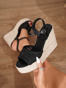 Detalle de la tira trenzada negra en sandalias de cuña con plataforma de esparto